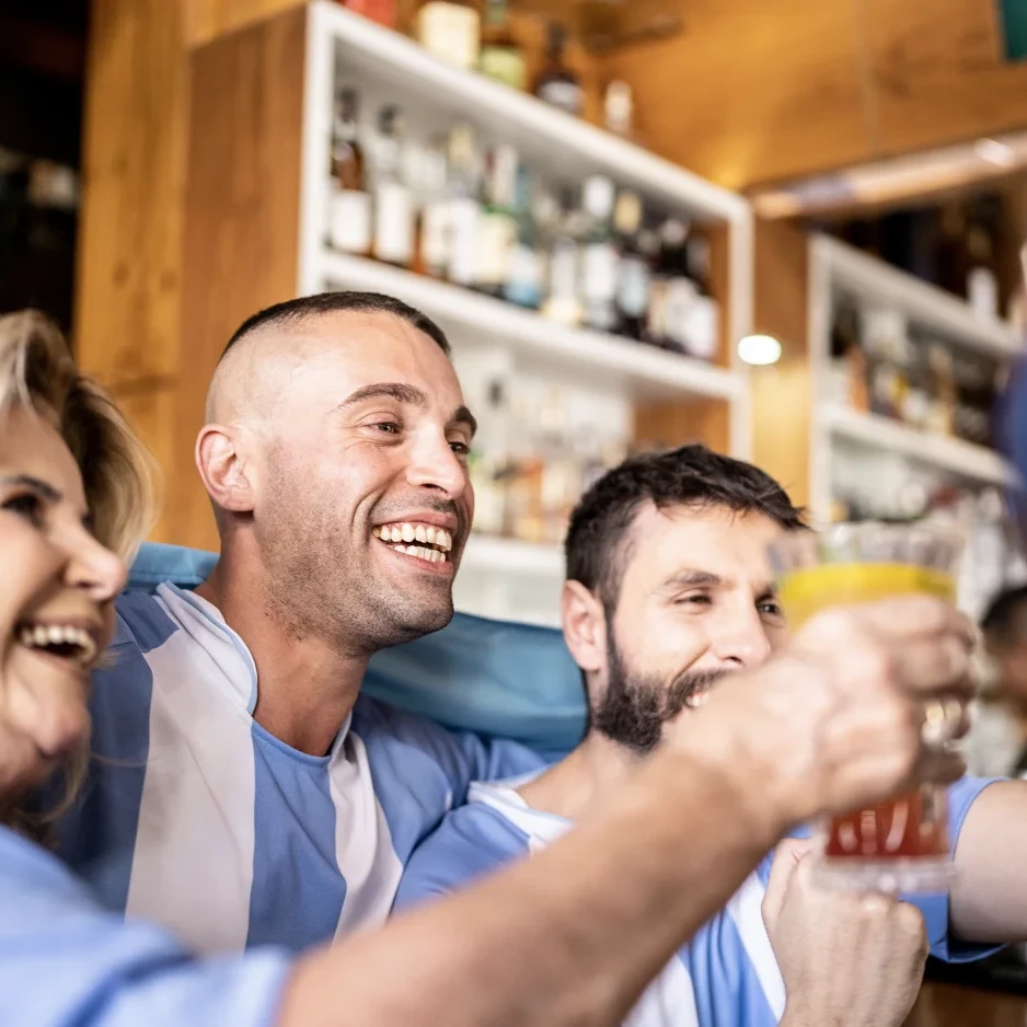 Friends smiling together at a restaurant, wearing matching sports jerseys.