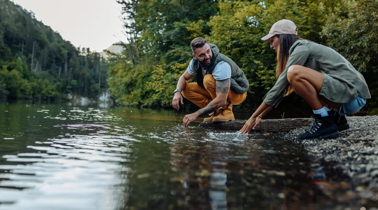 A man and woman spending time together outside by a stream.